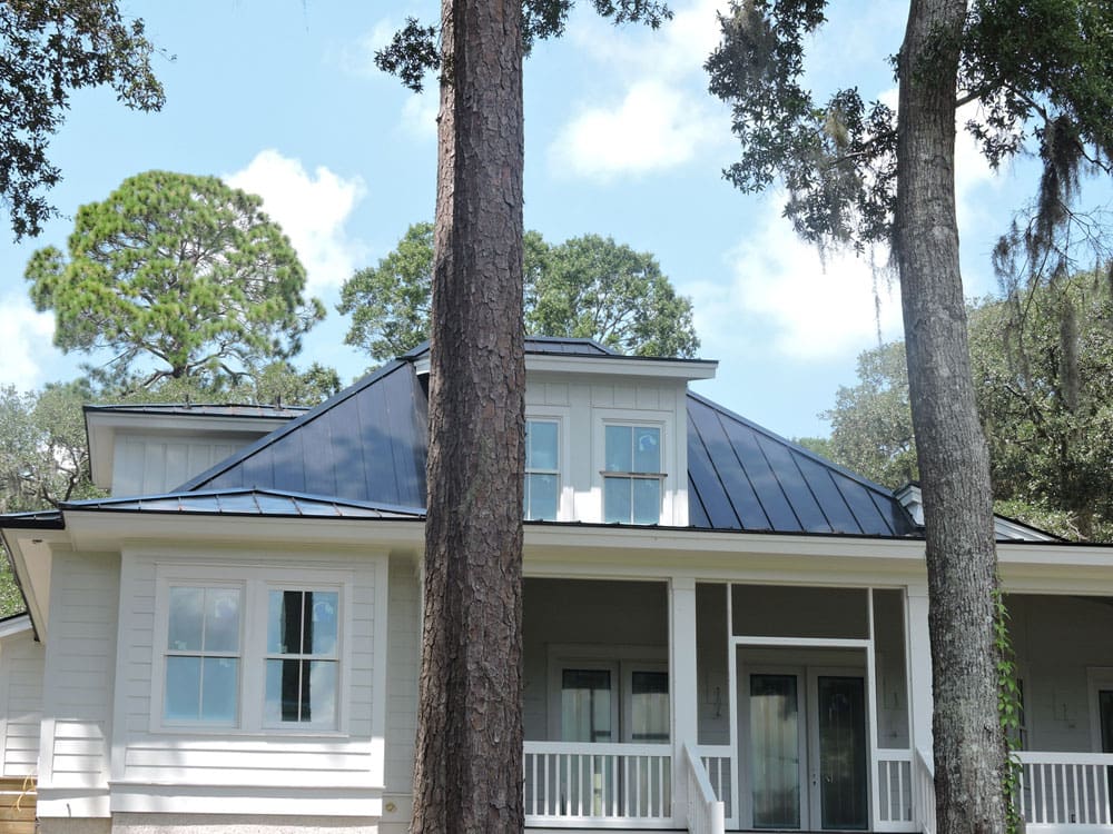 Blue metal roofing over a white, paneled house
